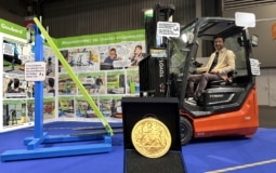 Jeremie Bourdillon de GOUBARD assis sur un chariot élévateur avec son invention primée et sa médaille d'or au concours Lépine 2026 : une station pour installer des rallonges de fourches sans descendre du chariot élévateur